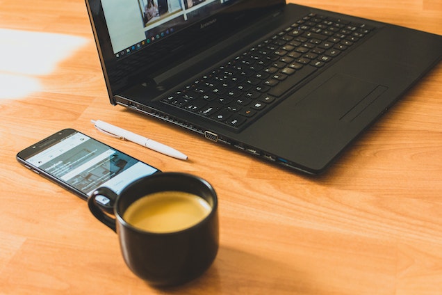 laptop coffee cup and phone on light wood desk